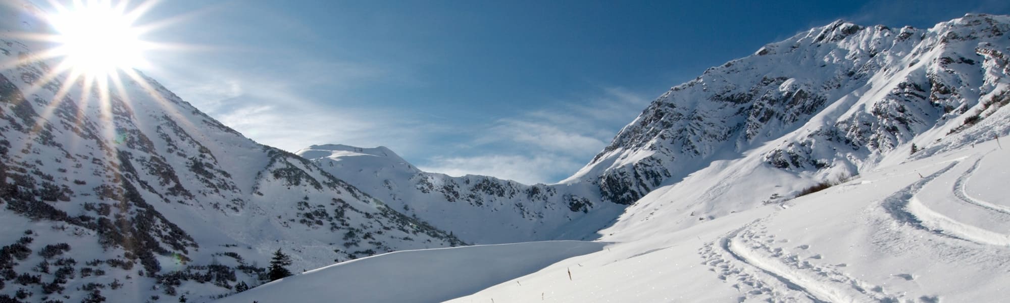 Vue ensoleillée sur le massif de Belledonne avec la neige et traces de skis, une station où Stay in Isère vous propose son hebergement Chamrousse.
